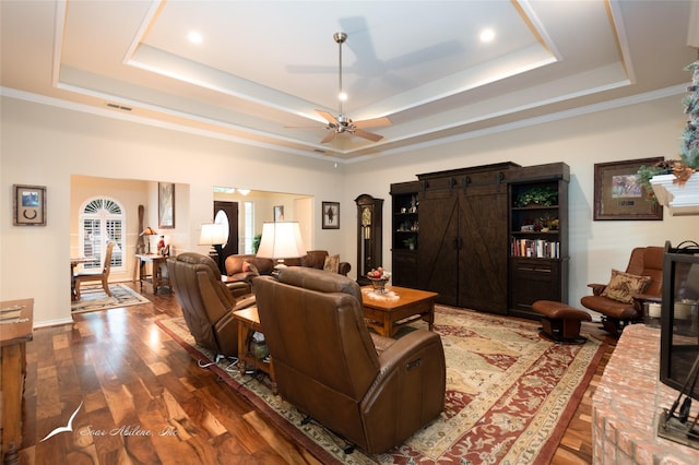 living room with hardwood / wood-style flooring, a tray ceiling, ceiling fan, and a barn door