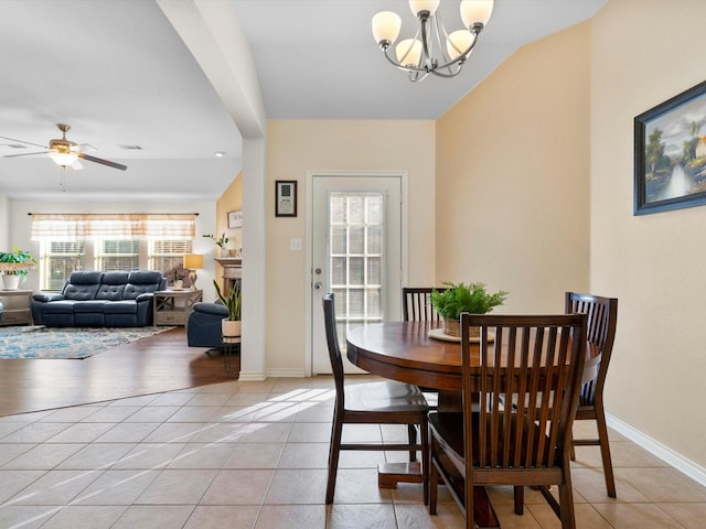 tiled dining room featuring ceiling fan with notable chandelier and vaulted ceiling