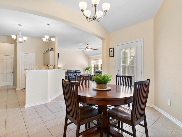 dining room with ceiling fan with notable chandelier, sink, light tile patterned floors, and vaulted ceiling