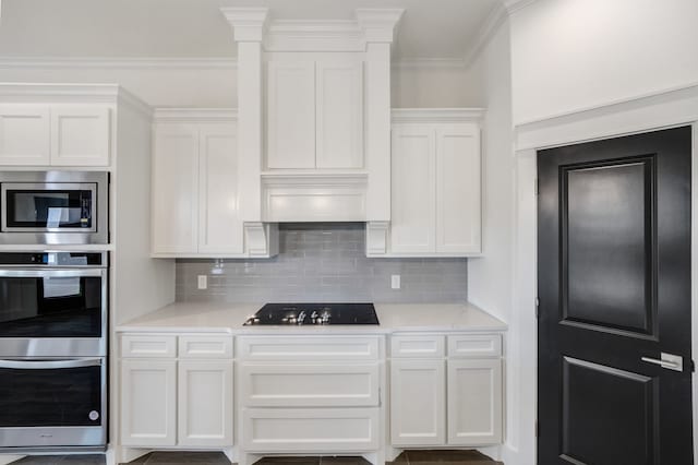 kitchen with backsplash, white cabinetry, ornamental molding, and stainless steel appliances