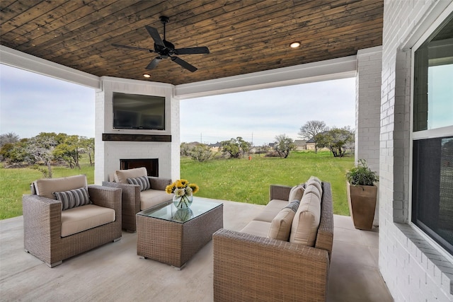 view of patio / terrace with ceiling fan and an outdoor living space with a fireplace