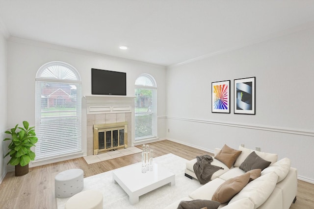 living room featuring a tile fireplace, hardwood / wood-style floors, and crown molding