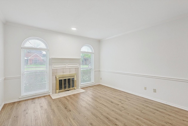 unfurnished living room featuring light hardwood / wood-style floors, ornamental molding, and a fireplace