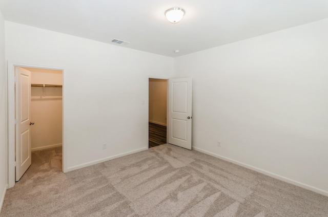 unfurnished bedroom with light carpet, a closet, and a spacious closet