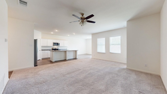 unfurnished living room featuring light colored carpet and ceiling fan