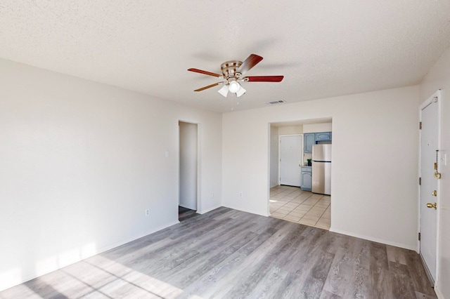 unfurnished room featuring ceiling fan, a textured ceiling, and light wood-type flooring