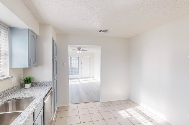 kitchen with light tile patterned flooring, dishwasher, sink, gray cabinetry, and a textured ceiling