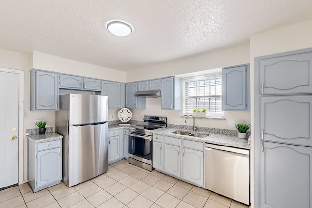 kitchen featuring appliances with stainless steel finishes, sink, a textured ceiling, and light tile patterned floors