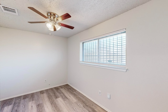 spare room featuring ceiling fan, light wood-type flooring, and a textured ceiling