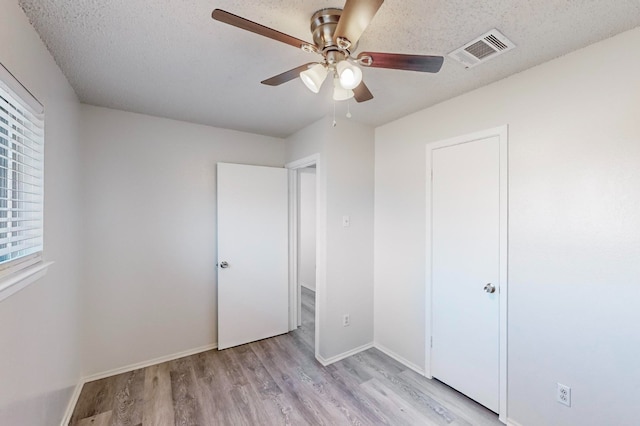 unfurnished bedroom with ceiling fan, a textured ceiling, and light wood-type flooring