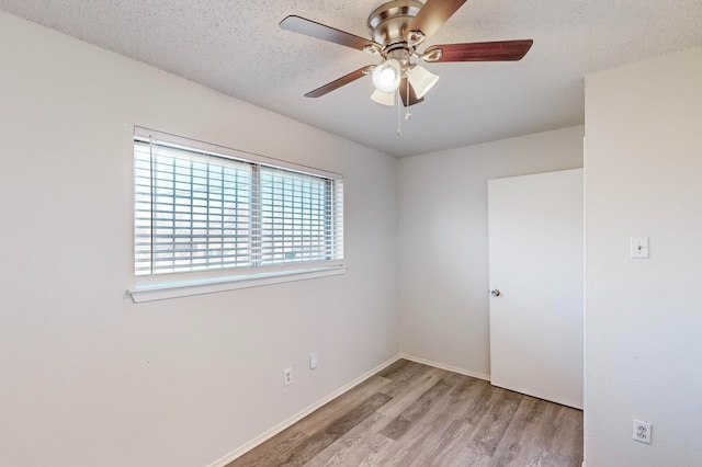 unfurnished room with ceiling fan, a textured ceiling, and light wood-type flooring