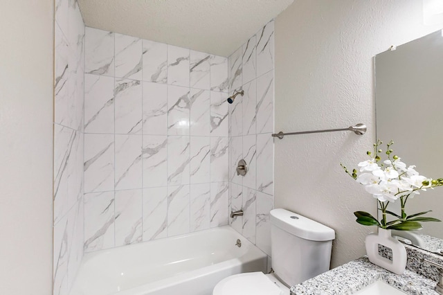 full bathroom featuring tiled shower / bath, vanity, toilet, and a textured ceiling