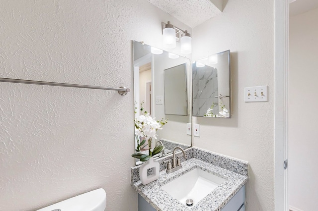 bathroom featuring vanity, toilet, and a textured ceiling