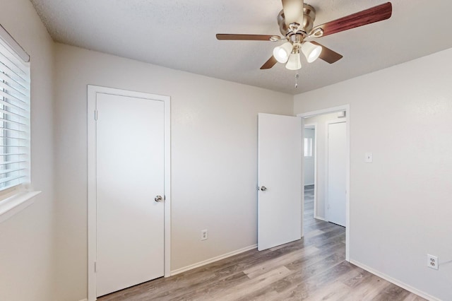 unfurnished bedroom featuring multiple windows, ceiling fan, and light wood-type flooring