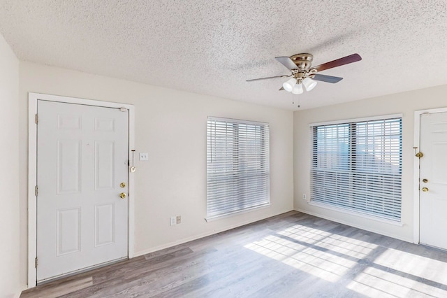 foyer entrance featuring ceiling fan, plenty of natural light, a textured ceiling, and light hardwood / wood-style flooring