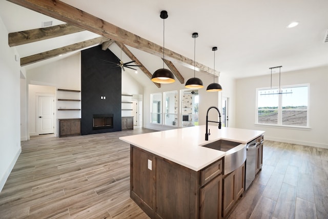 kitchen with dishwasher, ceiling fan, hanging light fixtures, a large fireplace, and a center island with sink