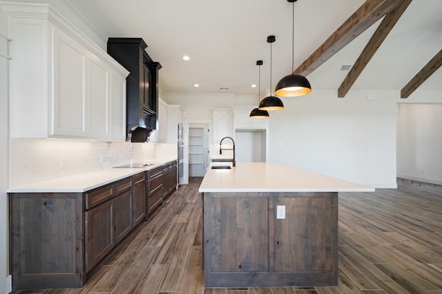 kitchen with a spacious island, white cabinets, beamed ceiling, sink, and hanging light fixtures