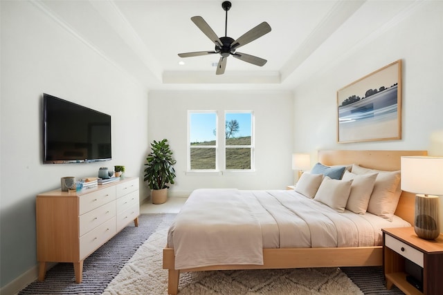 carpeted bedroom with ceiling fan, a tray ceiling, and crown molding