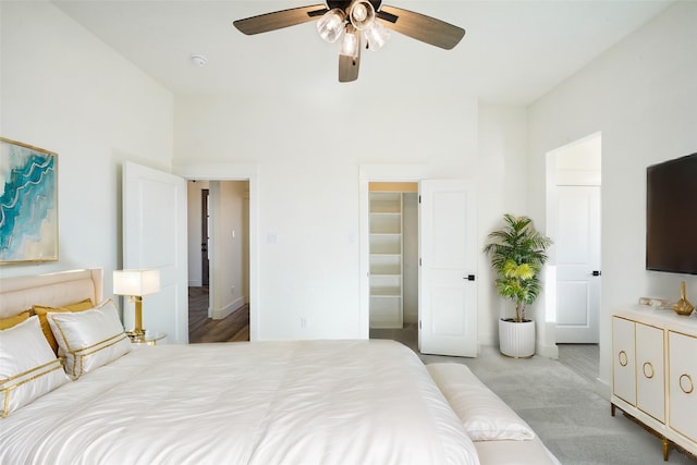 carpeted bedroom featuring a towering ceiling, a closet, ceiling fan, and a walk in closet