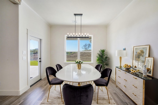 dining space with a healthy amount of sunlight, crown molding, and light wood-type flooring