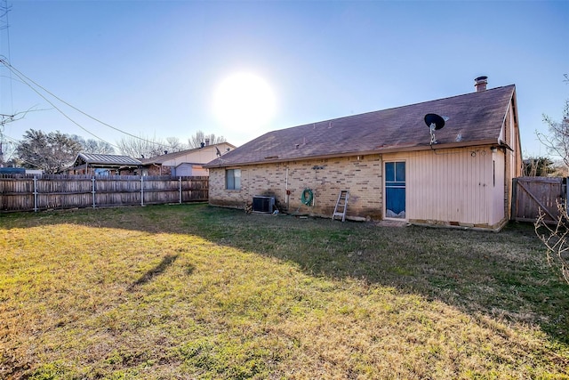 back of house with central AC unit and a yard