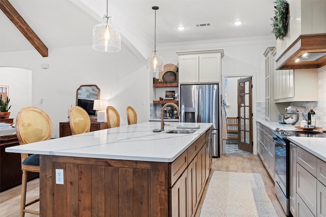 kitchen with beamed ceiling, light stone countertops, a kitchen island with sink, sink, and stainless steel appliances