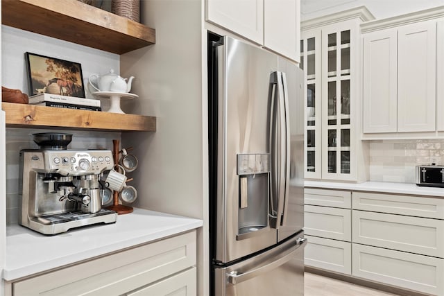 kitchen featuring stainless steel refrigerator with ice dispenser, decorative backsplash, and white cabinetry