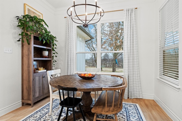 dining room with ornamental molding, light hardwood / wood-style flooring, and a notable chandelier