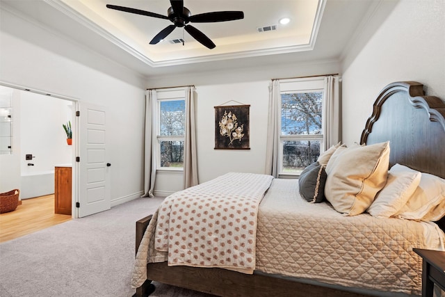 carpeted bedroom with ceiling fan, a raised ceiling, and crown molding