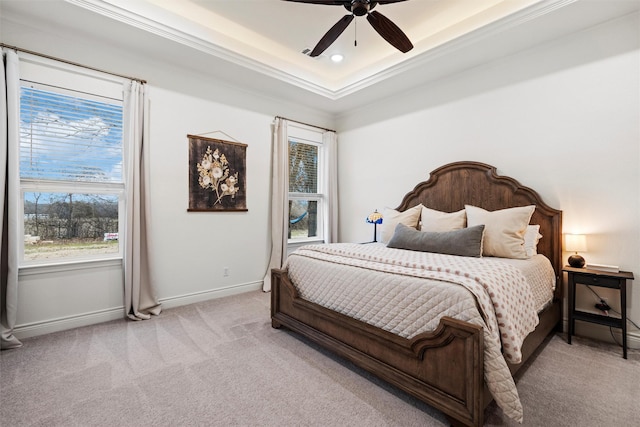 carpeted bedroom featuring ceiling fan, multiple windows, crown molding, and a raised ceiling