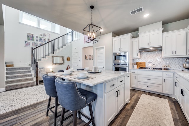 kitchen featuring white cabinets, backsplash, appliances with stainless steel finishes, and a center island