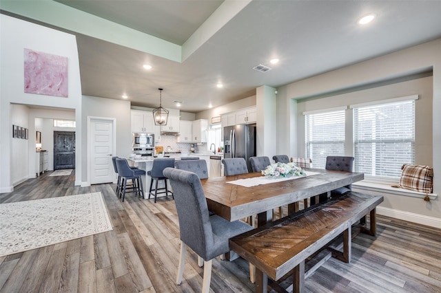 dining room with wood-type flooring, sink, and a notable chandelier