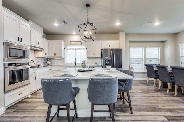 kitchen featuring white cabinets, a center island, stainless steel appliances, sink, and a breakfast bar area