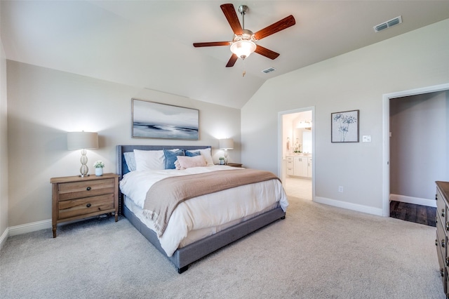 bedroom featuring vaulted ceiling, light colored carpet, ensuite bath, and ceiling fan