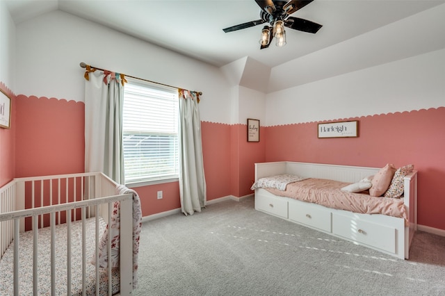 carpeted bedroom featuring ceiling fan, a nursery area, and vaulted ceiling