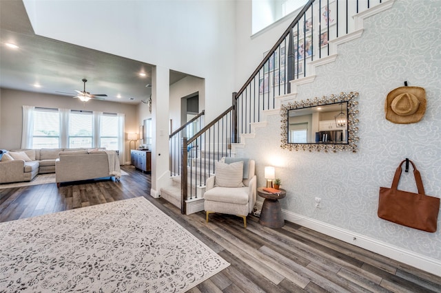 living room with hardwood / wood-style floors, a towering ceiling, and ceiling fan