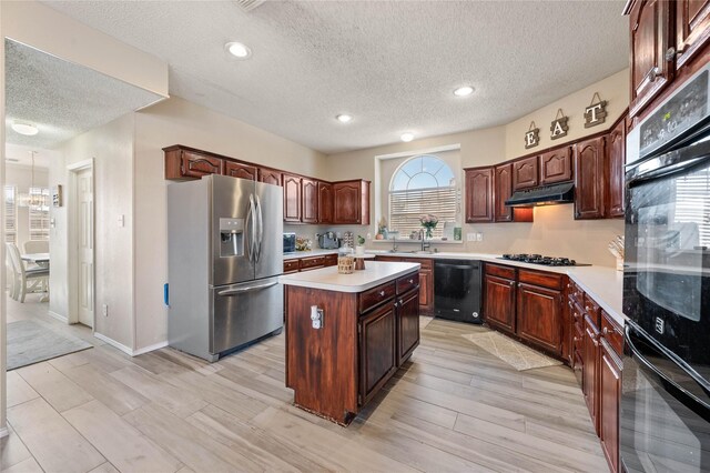 kitchen featuring a kitchen island, black appliances, a textured ceiling, and light hardwood / wood-style flooring