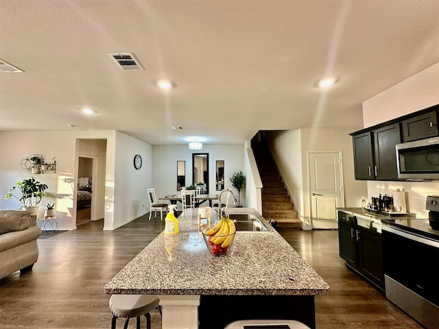 kitchen featuring light stone countertops, stainless steel appliances, sink, a kitchen island with sink, and a breakfast bar area