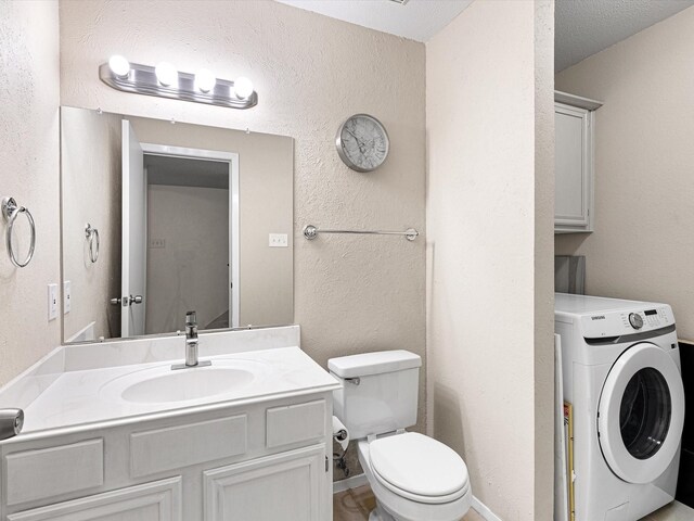 bathroom with a textured ceiling, toilet, washer / dryer, and vanity