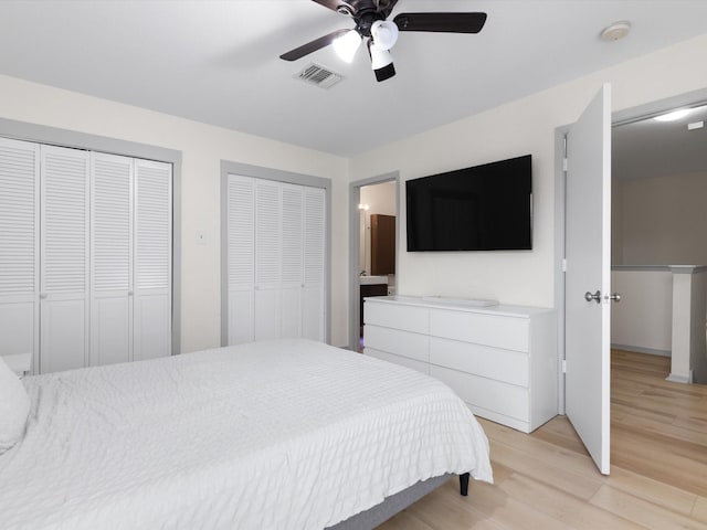 bedroom with multiple closets, ceiling fan, light hardwood / wood-style floors, and ensuite bath