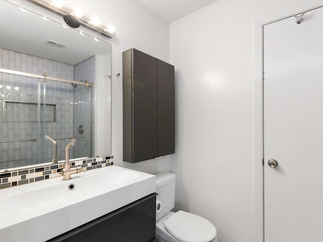 bathroom with toilet, backsplash, a shower with door, and vanity