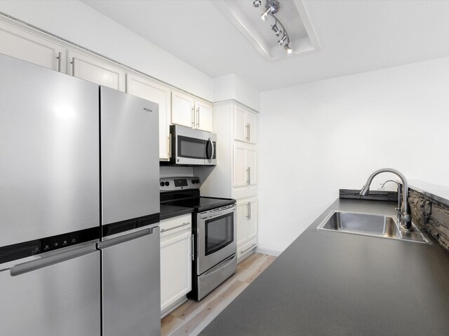 kitchen featuring sink, white cabinets, appliances with stainless steel finishes, and light hardwood / wood-style flooring