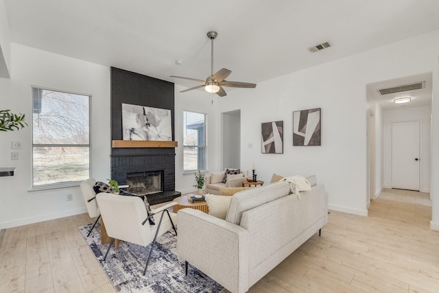 living room featuring a fireplace, light wood-type flooring, and ceiling fan