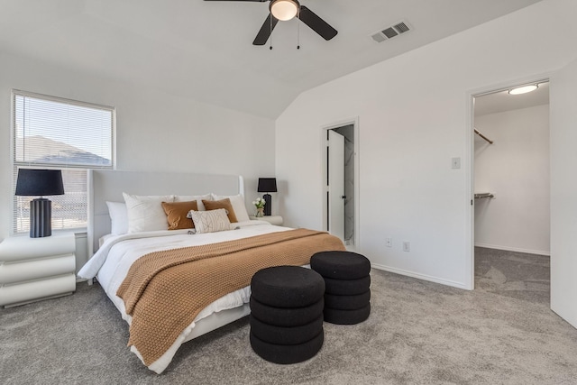 carpeted bedroom featuring lofted ceiling, ceiling fan, and a walk in closet