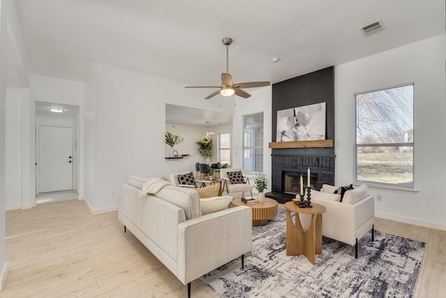 living room featuring a fireplace, light wood-type flooring, and ceiling fan