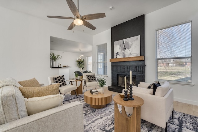 living room featuring hardwood / wood-style flooring, ceiling fan, and a fireplace