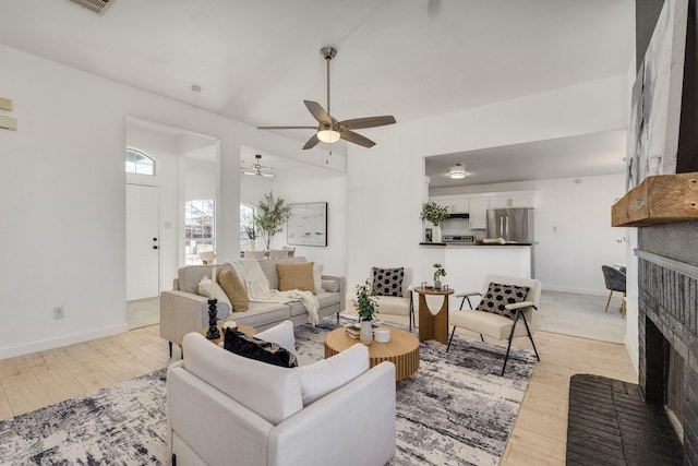 living room featuring a brick fireplace, light hardwood / wood-style floors, and ceiling fan