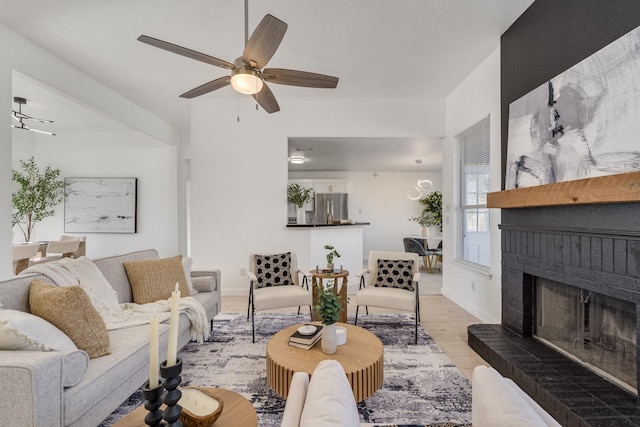 living room featuring ceiling fan, light hardwood / wood-style floors, and a brick fireplace