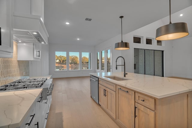 kitchen featuring appliances with stainless steel finishes, hanging light fixtures, sink, a large island with sink, and light brown cabinets