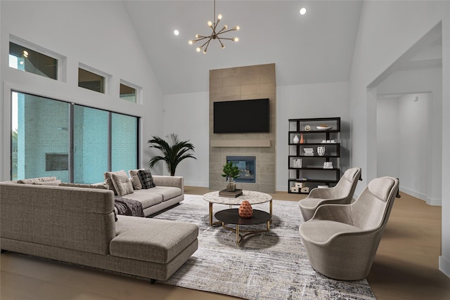 living room featuring a tiled fireplace, a chandelier, hardwood / wood-style flooring, and a towering ceiling